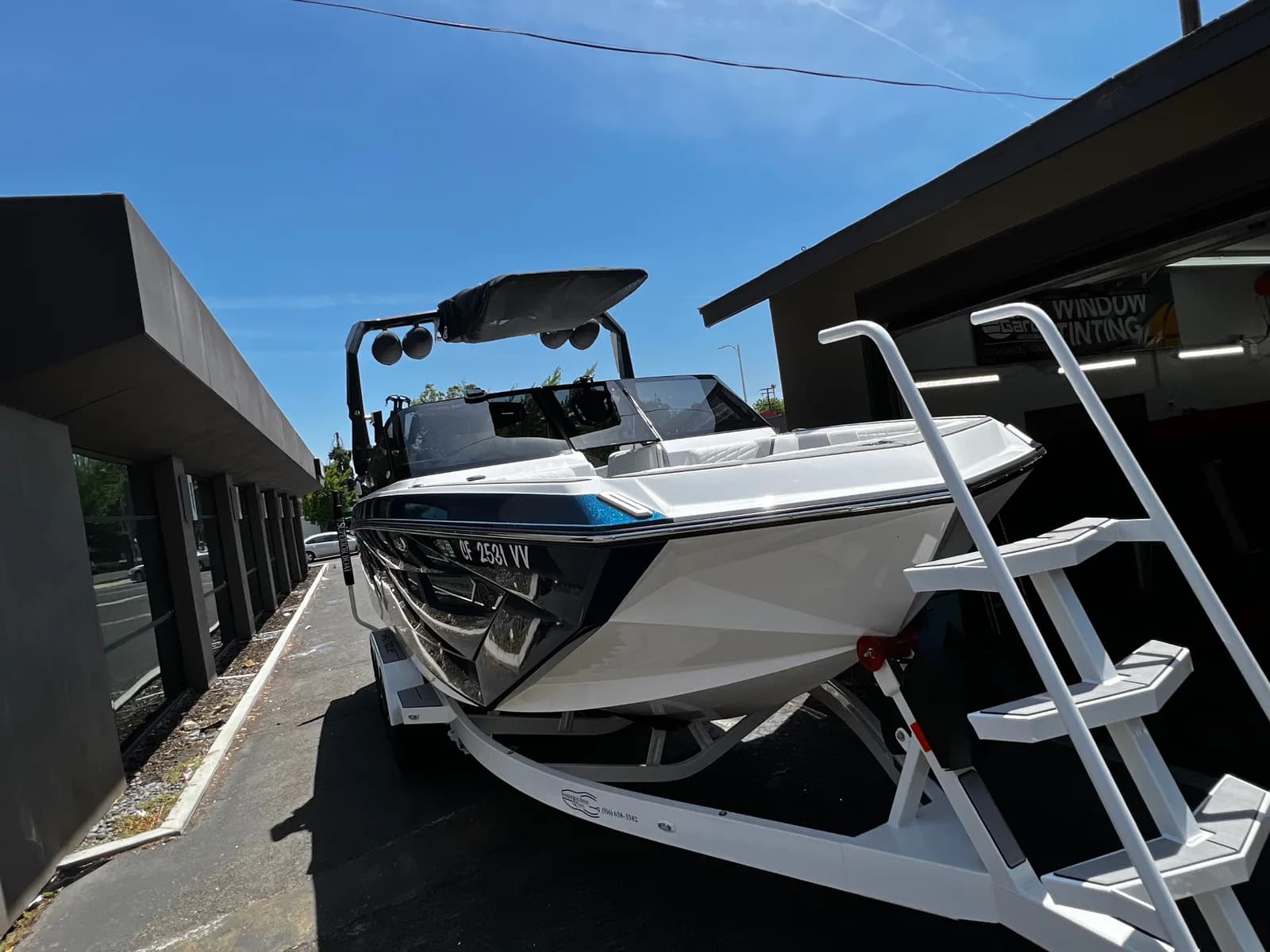 White boat on trailer receiving professional marine window tinting services