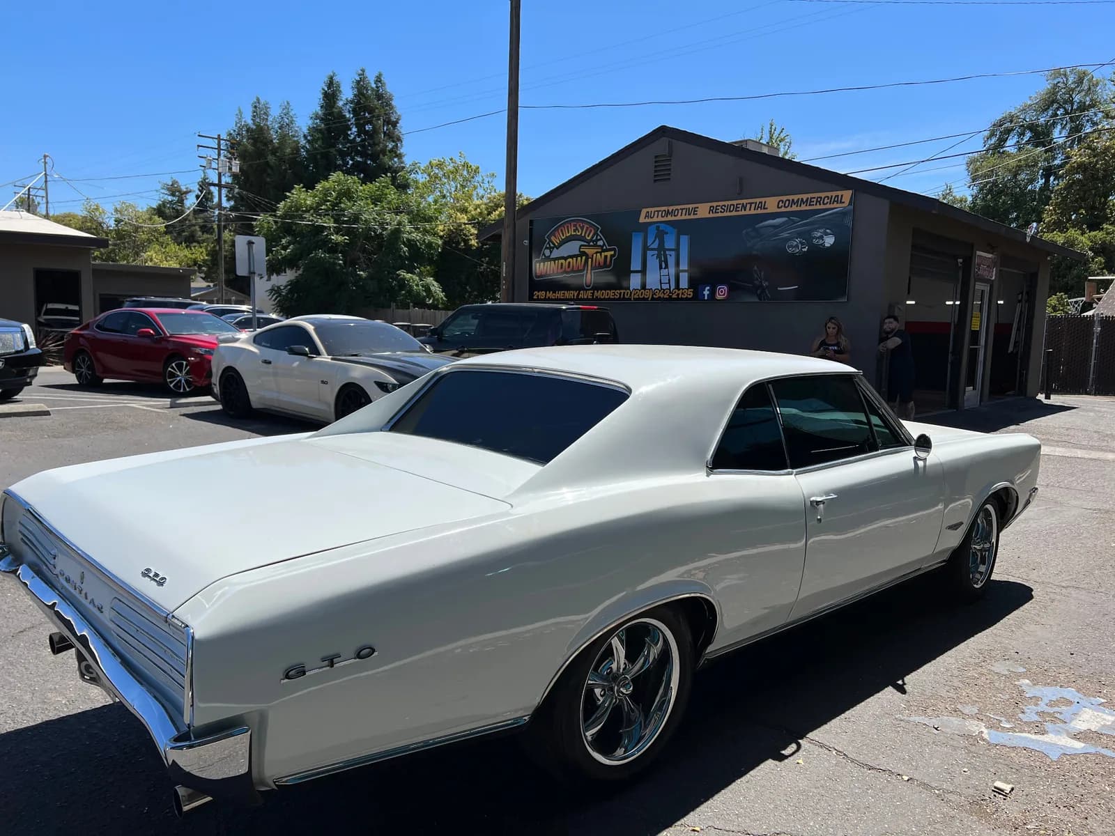 White classic Pontiac GTO with professional window tinting in front of Modesto Window Tint storefront