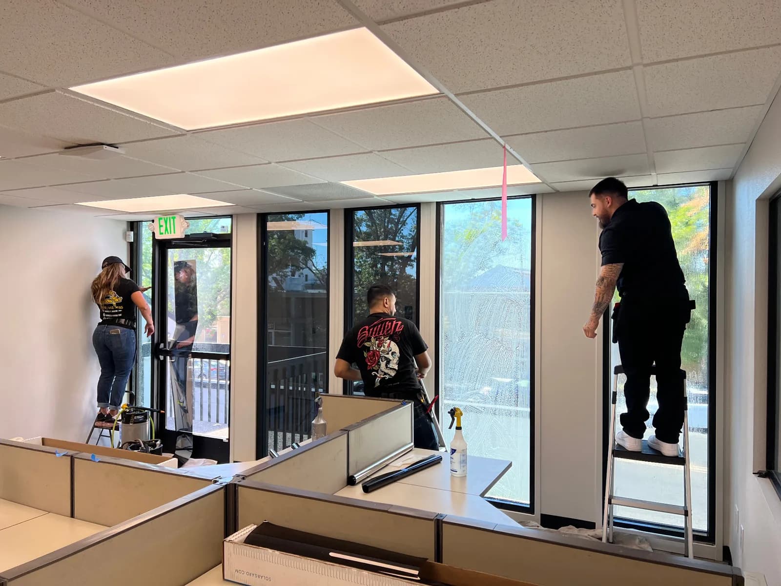 Professional technicians installing window tint in modern facility with proper tools and equipment