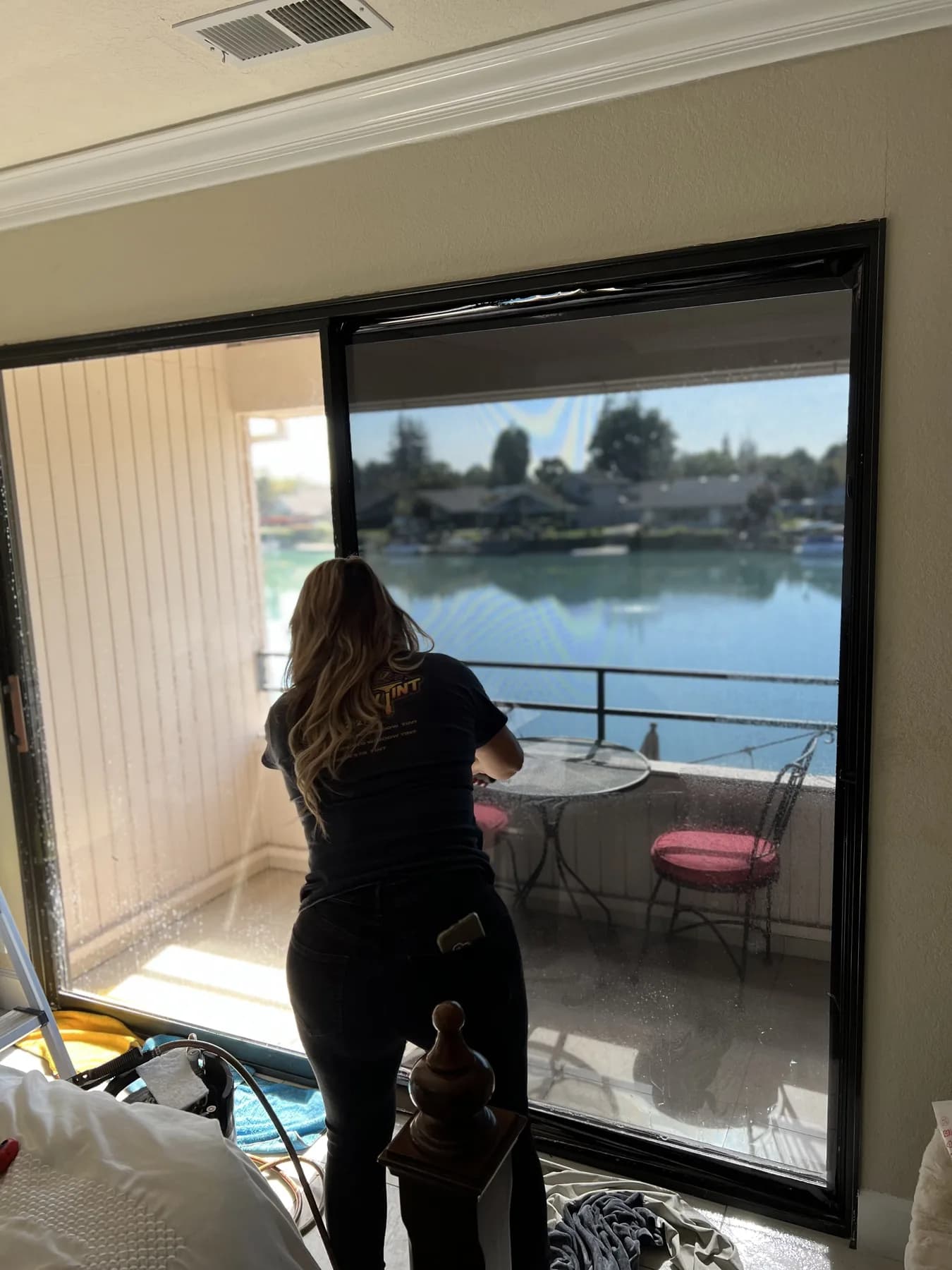 Installer fitting window film in a home with a waterfront view