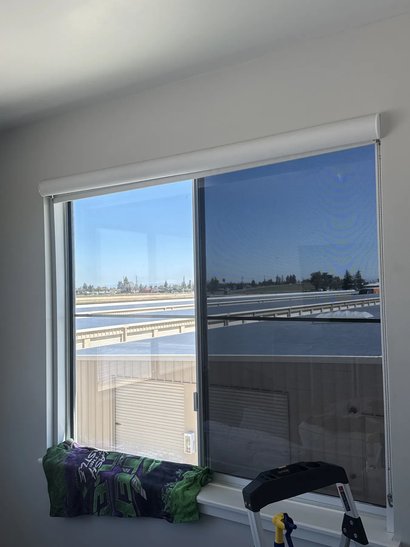 Interior office window with solar film and screens overlooking a storage lot