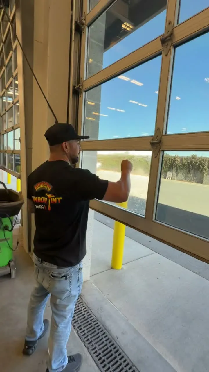 Modesto Window Tint installer finishing window film on a glass bay door at Stanislaus County Public Works